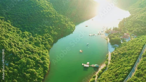 Oyster farm in Gulf of Lima on Istrian peninsula in Croatia. Giant mountains with lush forests surround bay water at sunrise in summer. Aerial view photo