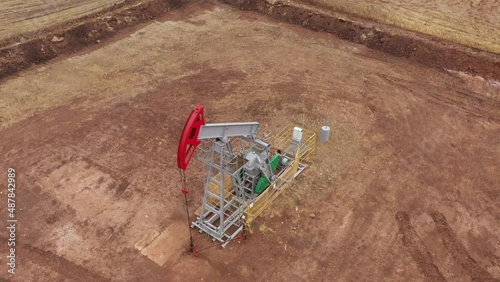 Pump jack in vast oil fields in Russia. Pipelines transporting oil from oil pumps, aerial drone shot