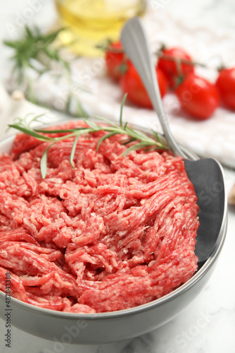 Fresh minced meat in ceramic on white marble table, closeup