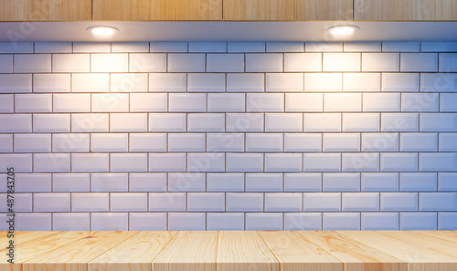 Front view of empty wood counter with lighting on white tiles wall and wooden countertop in modern kitchen room 
