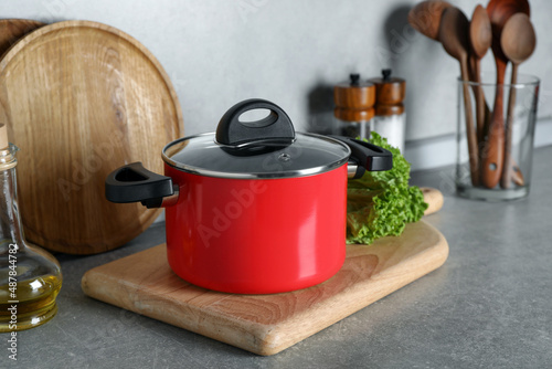 Pot with lid and other cooking utensils on grey countertop in kitchen