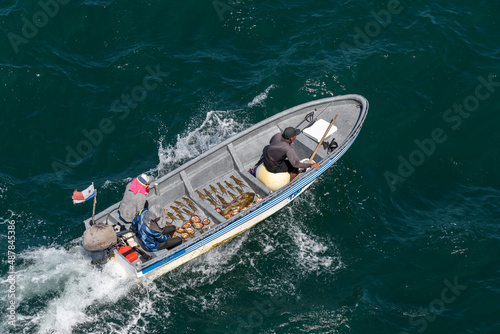 Small fishing boat with fishermen sailing at sea. Fish, shells, lobsters in boat. Top view. © Alexey Seafarer