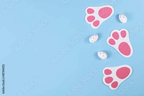 Easter flat lay with cute rabbit feed prints and dotted eggs on blue background