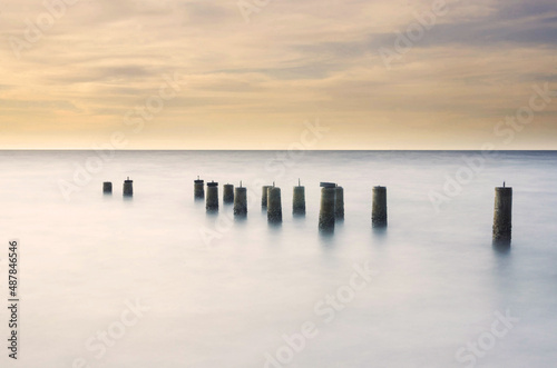 Scenery of a beautiful sunset with a pillars of jetty left over © nadzlanimages
