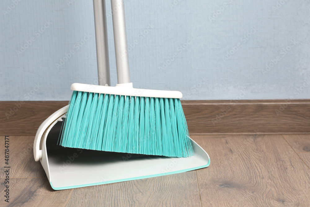 Plastic broom with dustpan near light blue wall indoors - obrazy, fototapety, plakaty 
