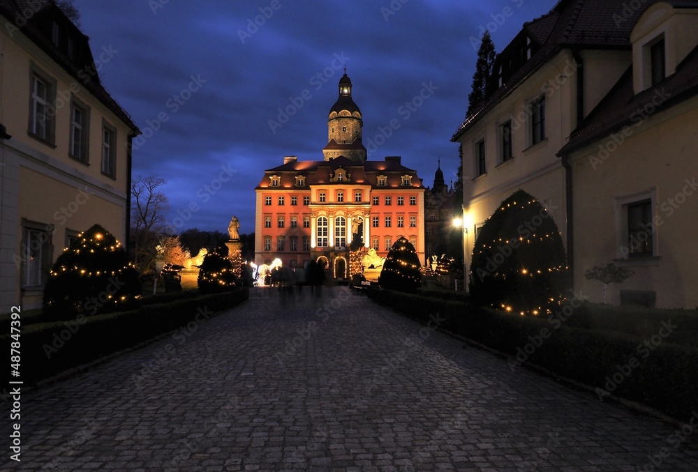 Książ Castle illuminated at dusk seen from the entrance