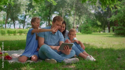 Wallpaper Mural Smiling family waving hands communicate using tablet on nature in summer day. Torontodigital.ca