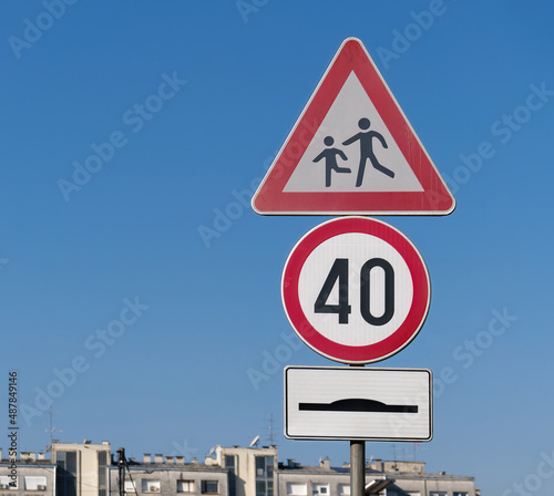 Warning pedestrian crossing sign, round speed limit 40 sign, and hump sign on a metallic pole