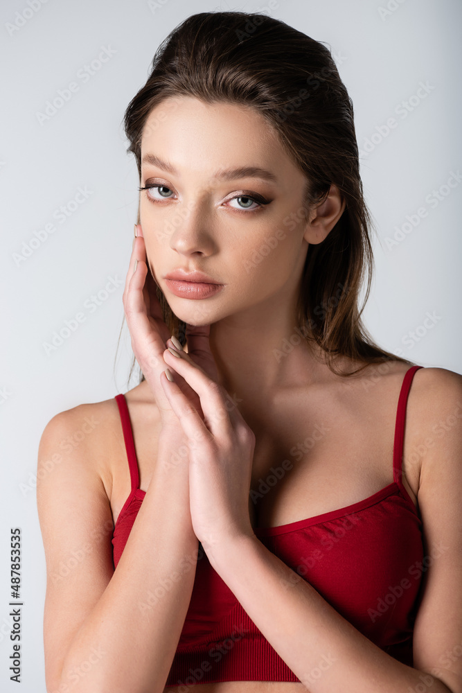 brunette young woman in red crop top looking at camera isolated on grey. brunette young woman in red crop top looking at camera isolated on grey.