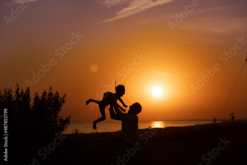 Fototapeta Naklejka Na Ścianę i Meble -  Silhouette of a man and a child against the sunset.Dad raises his son 