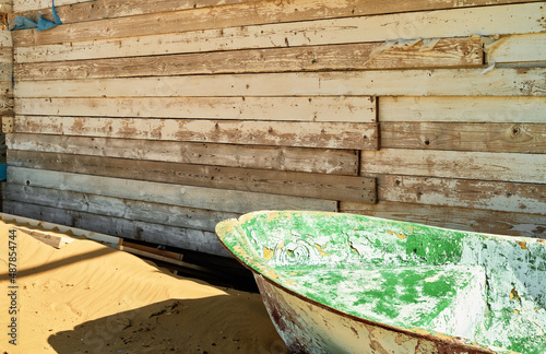 Abandoned fishing boat on the beach, by the old wooden barn, close-up, sunlight © Ed