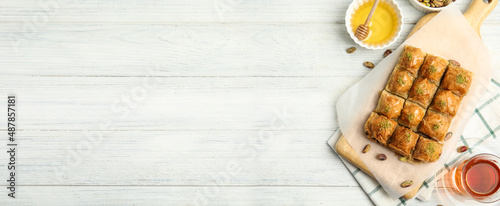 Delicious sweet baklava on white wooden table, flat lay. Space for text
