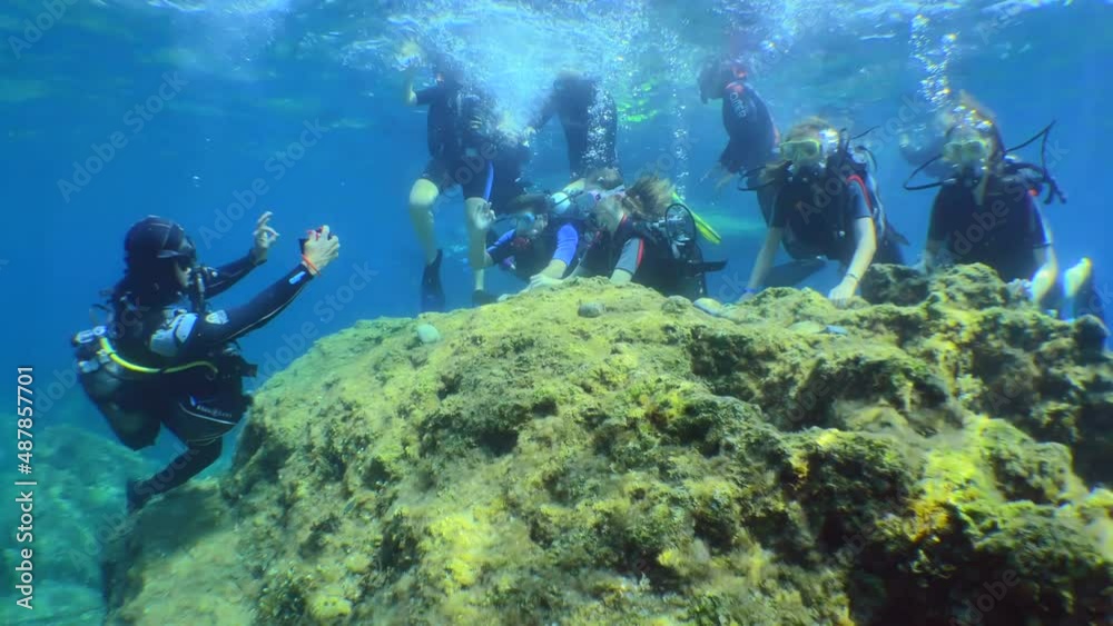 Diving: a diving instructor takes a photo of divers during their first dive.