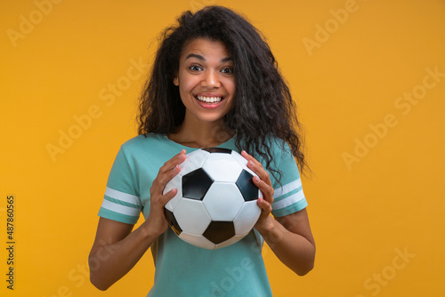 Studio portrait of football fan girl with the ball in hands smiling being happy to support favorite team © wpadington