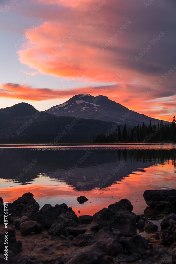 Fiery sunrise at lake with mountains, reflections and unique clouds