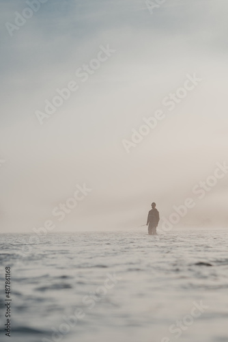 Telephoto angle of a male angler spey fishing for wild steelhead on scenic river in the fog