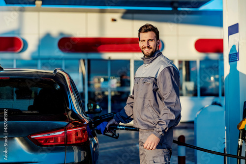 Schilderij op canvas A gas station worker filling up car tank and smiling at the camera