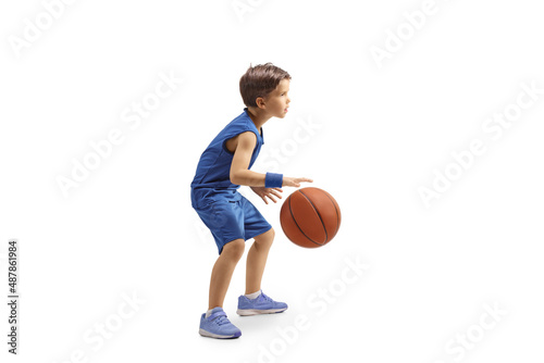 Full length profile shot of a boy in a blue jersey playing basketball