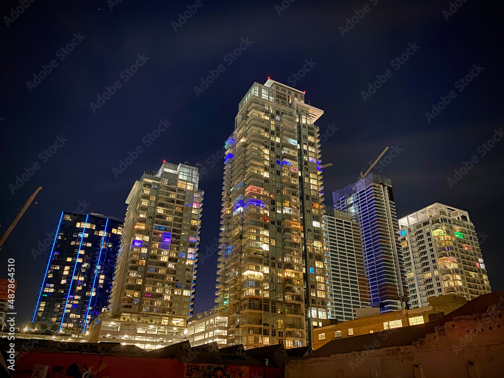 Obraz premium Group of high-rise towers of apartments in Downtown Los Angeles, some under construction, lit up with different colors at night