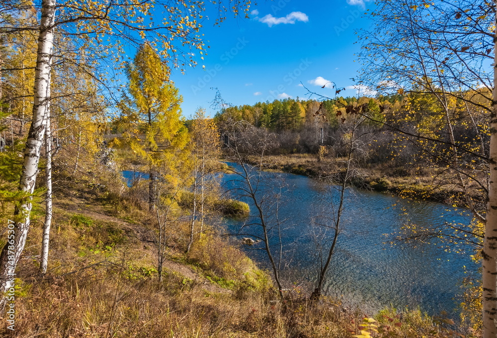 Fototapeta premium Autumn landscape with river, trees, grass and blue sky