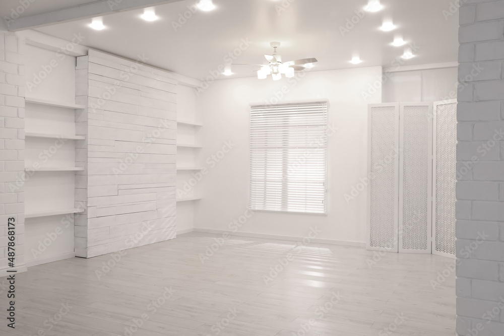 Obraz premium Empty room with textured wall, stylish wooden shelves and large window