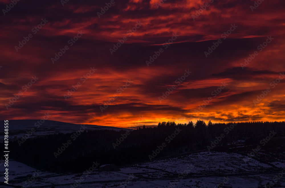 Dramatic, blazing sunset over snow covered hills and mountains (Weardale, the North Pennines, County Durham, UK)