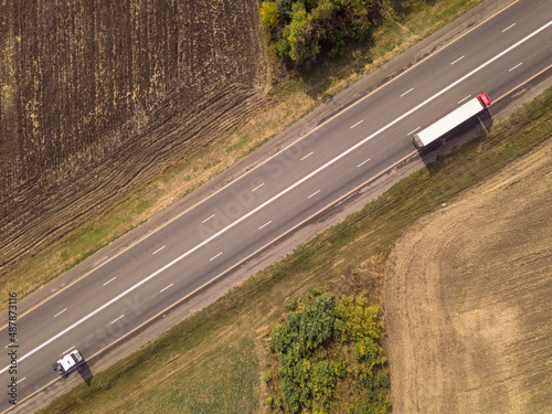 Aerial top down shot of highway with truck trailer and the car.