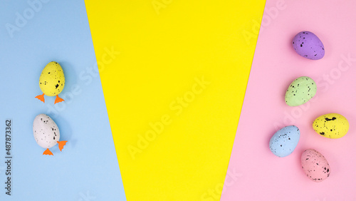 Easter flat lay composition with eggs on vibrant pastel blue yellow and pink bakcgorund.  Spring holidays concept. MInimal copy space photo