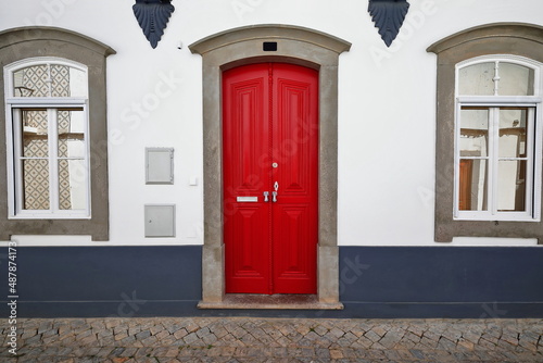 Red lacquered door in whitewashed facade-Neoclassical townhouse-mirroring windows. Tavira-Portugal-111