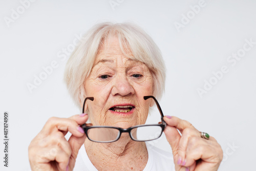emotional elderly woman in casual t-shirt and glasses light background