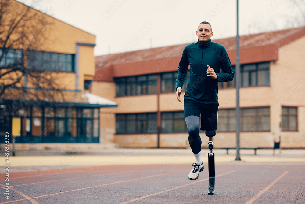Fototapeta premium Male runner with prosthetic leg running during practice on outdoor sports field.