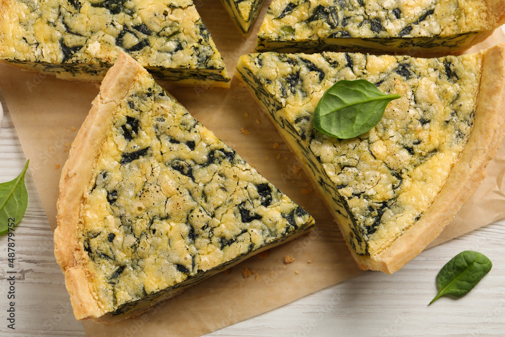 Obraz na plátně Cut delicious spinach pie on white wooden table, flat lay