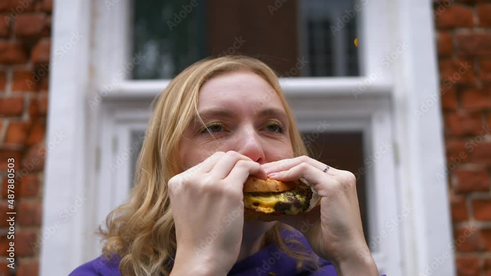 Close up view of woman eating burger, fast food outdoors in the city. Close up view of woman eating burger, fast food outdoors in the city.