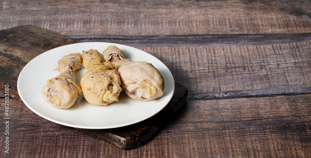 Steamed or boiled chicken thigh on dark wooden background, stock photo, selective focus