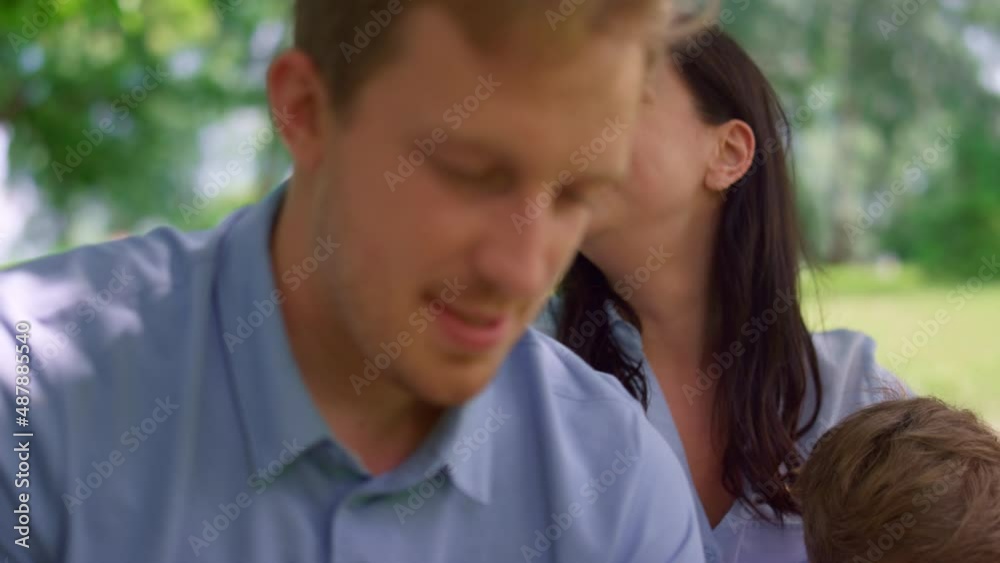 Young couple watching tablet on nature close up. Happy family have fun on picnic Young couple watching tablet on nature close up. Happy family have fun on picnic