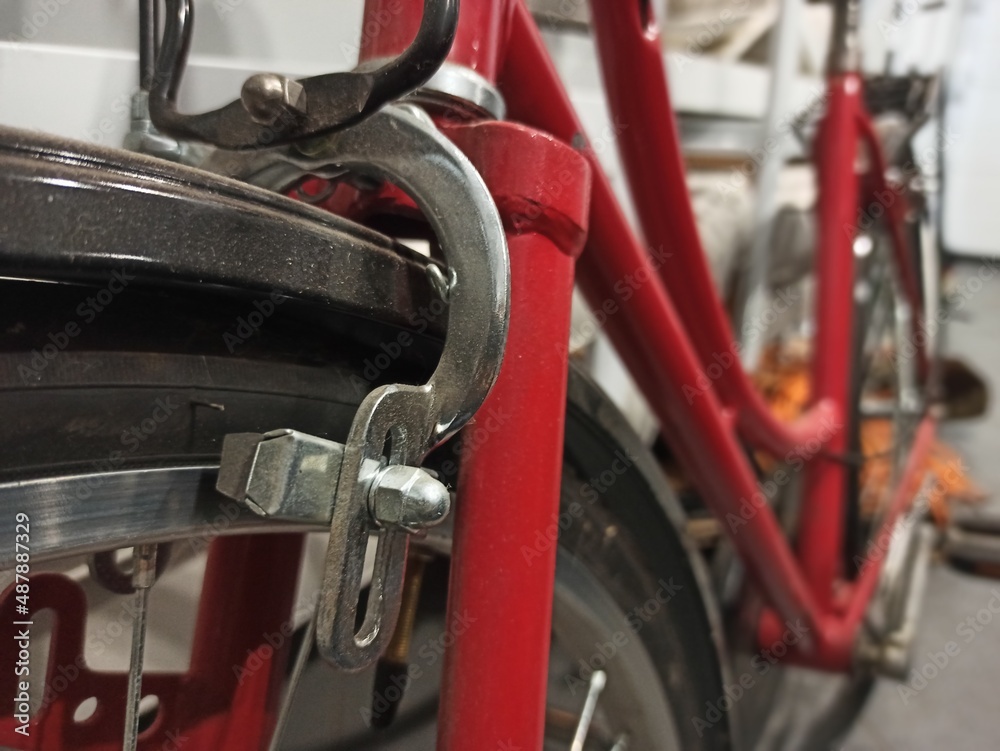 closeup of red women's walking bicycle brake with spokes and wheel with silver bolt closeup of red women's walking bicycle brake with spokes and wheel with silver bolt