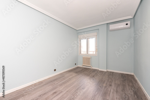 empty bedroom with green walls and parquet floor with air conditioner and white aluminum window