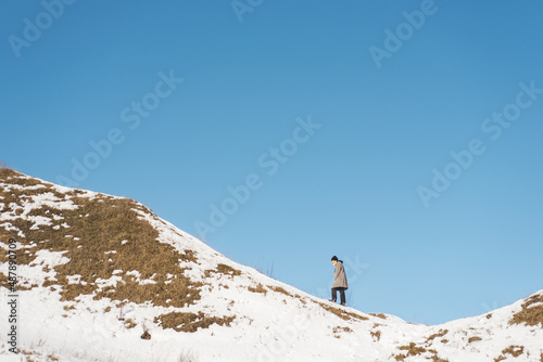 Woman in overcoat walking up the mountain range. A person climbi