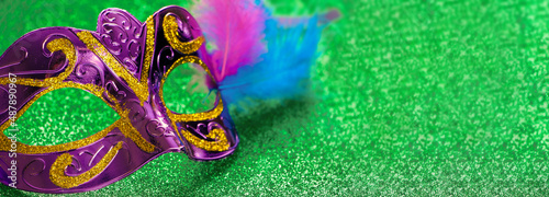 Purple carnival mask on green shiny background. Mardi Gras or Fat Tuesday symbol.