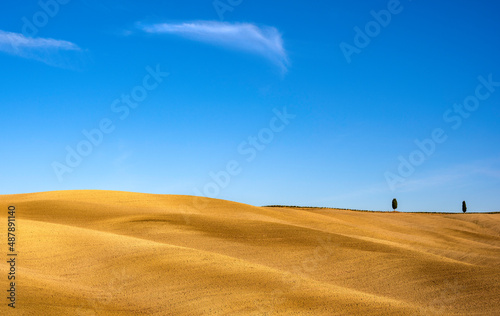 Beautiful landscape of a plowed field and a blue sky in Tuscany, Italy