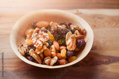 Mix fruit and nut mix in a small wooden cup. Healthy choice for energy. Raisins, walnut, almond in a bowl. Nature product