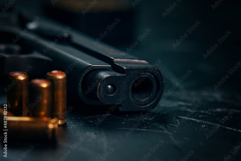 Weapons on concrete background. Close-up of gunpoint and bullets on table. Firearms and ammunition. Concept of crime and physical evidence. Pistol for defense or attack.