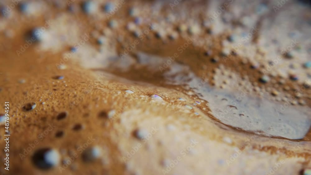 Macro view of a coffee foam with brown bubbles during brewing fresh Turkish black coffee drink.
