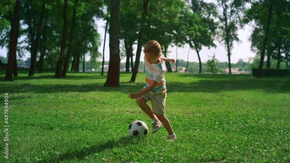 Energetic boy warming up before football match. Focused child play on field. Energetic boy warming up before football match. Focused child play on field.