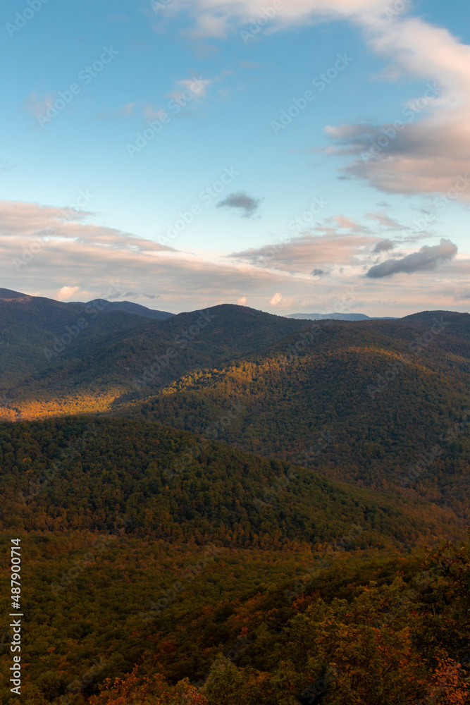 View of Mountains with Autumn Foliage Trees with a Cloudy Blue Sky View of Mountains with Autumn Foliage Trees with a Cloudy Blue Sky