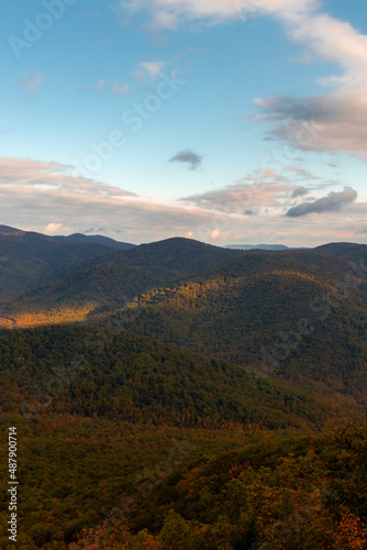 View of Mountains with Autumn Foliage Trees with a Cloudy Blue Sky