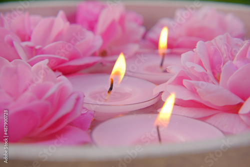 Rose candles.Pink burning candles and pink roses in water.Aromatherapy and spa concept.Candle flame. Candles background.