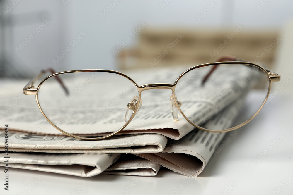 Stack of newspapers and glasses on white table indoors, closeup Stack of newspapers and glasses on white table indoors, closeup