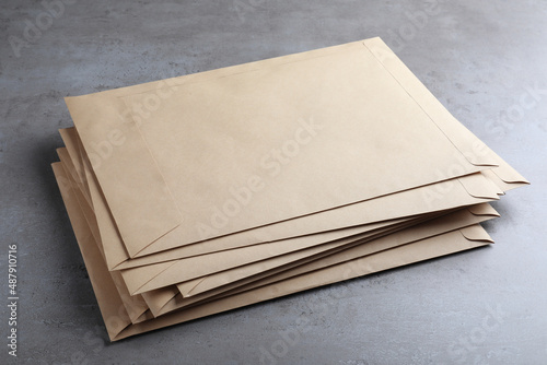 Stack of kraft paper envelopes on grey table photo