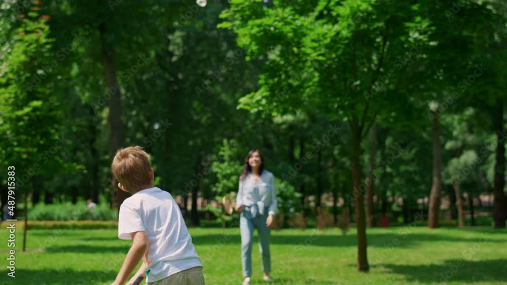 Joyful mother play badminton with son in park. Happy family have fun outdoor. Joyful mother play badminton with son in park. Happy family have fun outdoor.